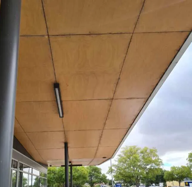 The underside of a shopfront awning after cleaning, with the panel joints and light fittings visible.